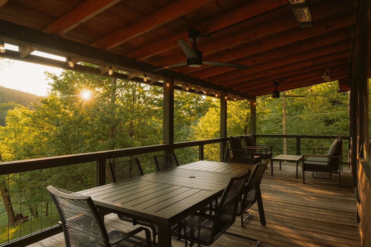 A covered cottage deck with a dining table, lit by low evening sun