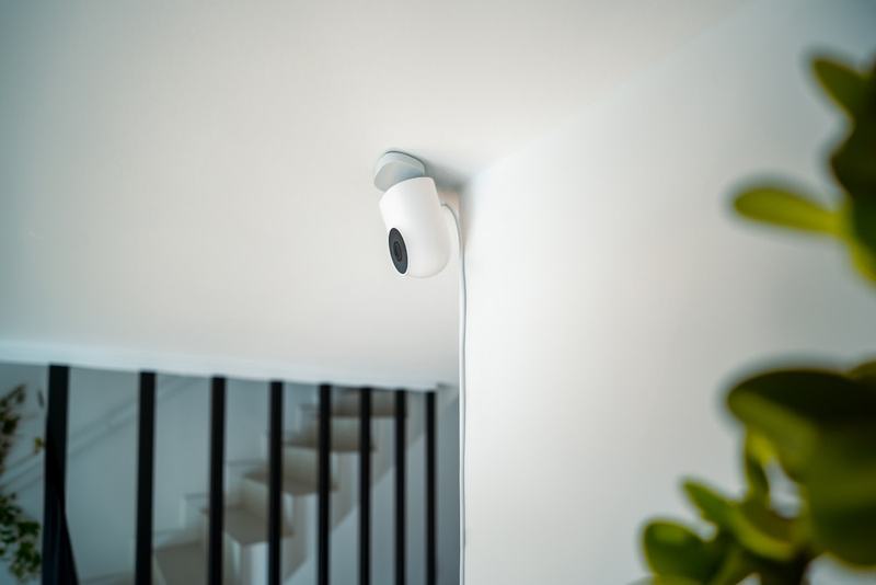 A small white security camera on an interior ceiling